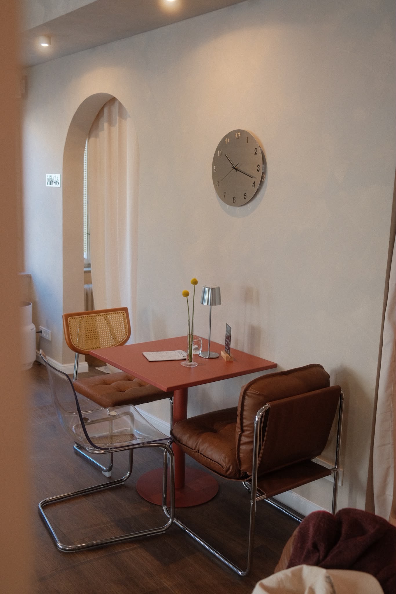 Gemütlicher Sitzplatz mit roten Tisch und gepolsterten Stühlen im Café Cura